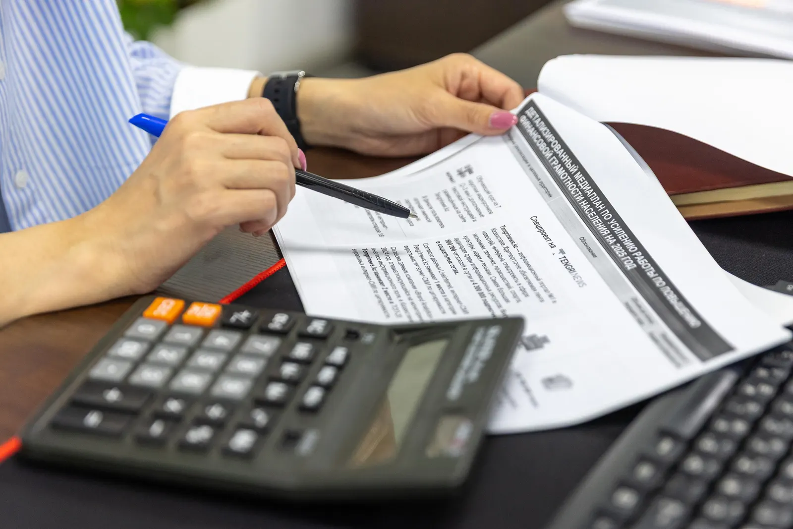 Hands working through financial documents with a pen and a calculator.