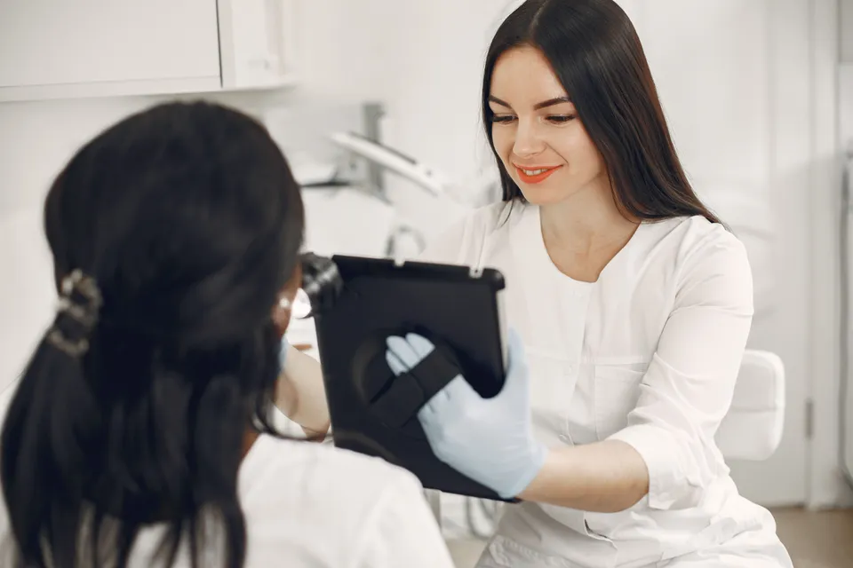 A practitioner in gloves showing a customer something on a tablet before a treatment.
