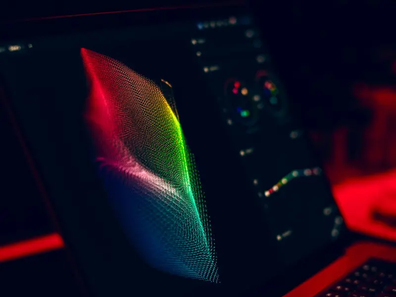 A glowing, computer-generated wave of coloured points displayed on a laptop screen