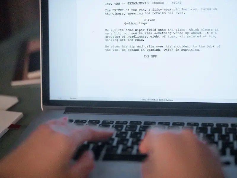 Hands typing a script on a laptop, the page of text filling the screen