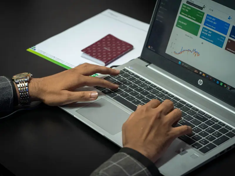 Hands typing on a laptop showing a dashboard of campaign figures and charts
