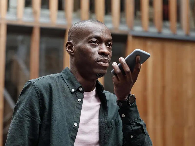 A man holding a phone close to his mouth to speak a voice command