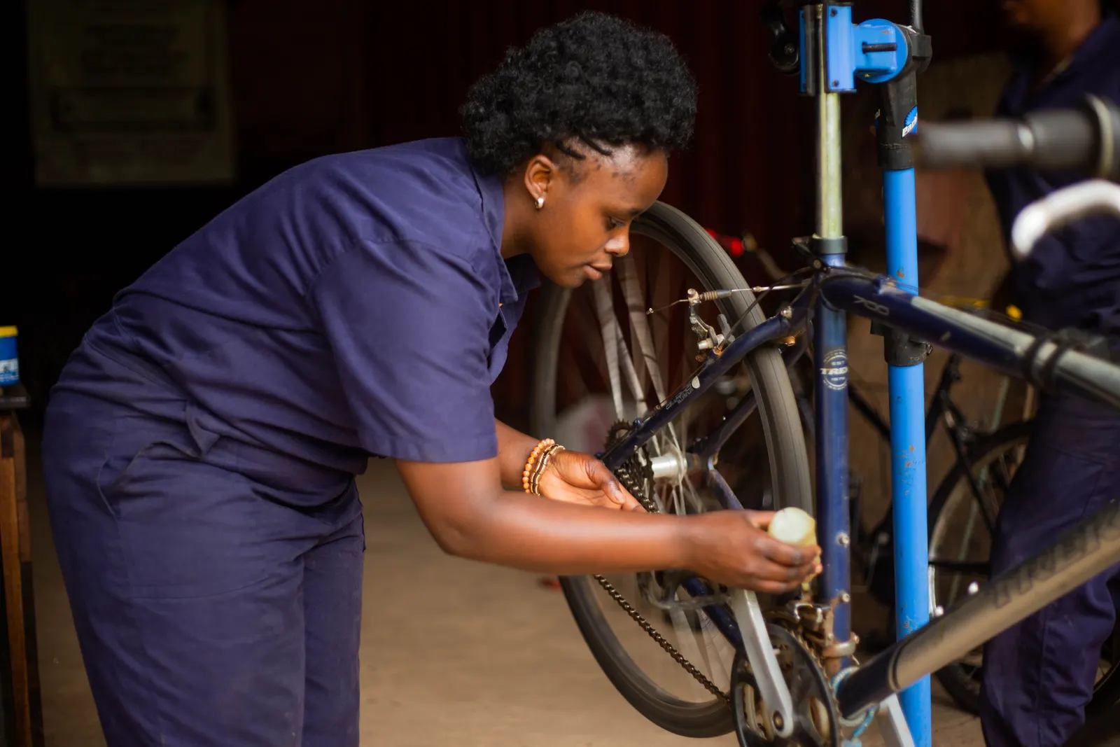 A mechanic servicing a bicycle clamped on a workshop stand.
