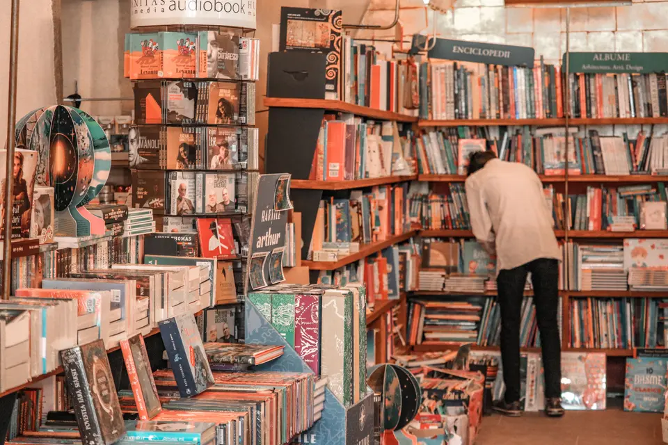 A man browsing the crowded shelves of a small bookshop.