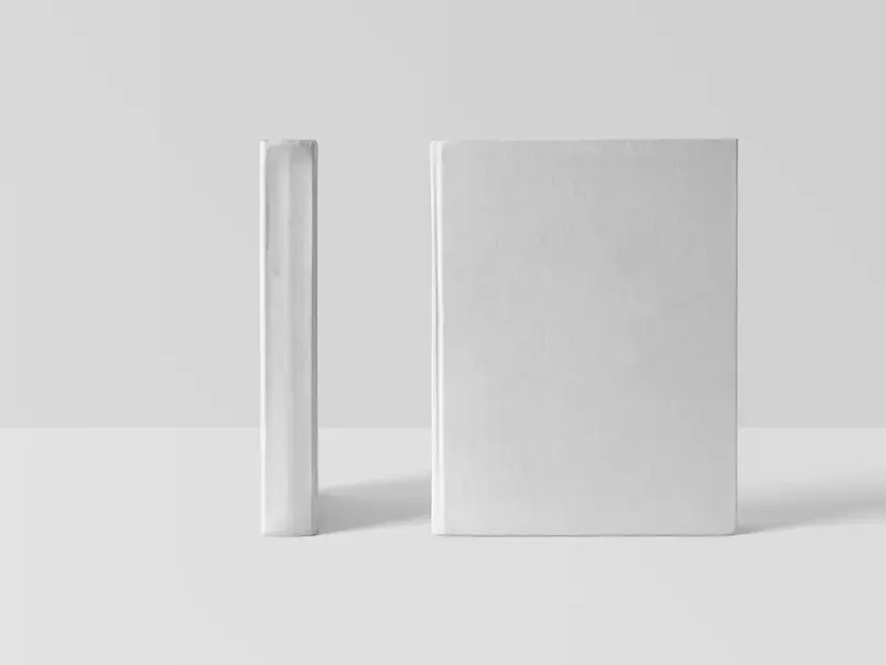 Two blank white hardback books standing upright, one showing its spine, ready for a cover