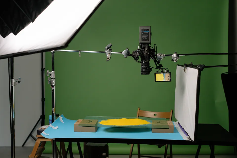 A camera rigged over a table in a green-screen studio, set up to film a product shot.