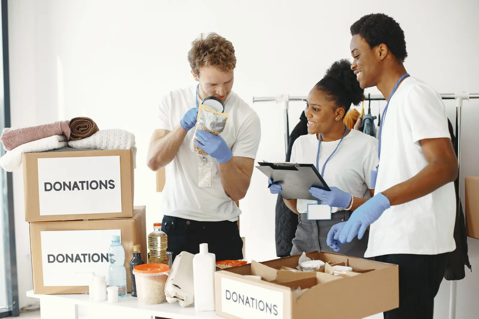 Volunteers in gloves sorting clothes and supplies into donation boxes.