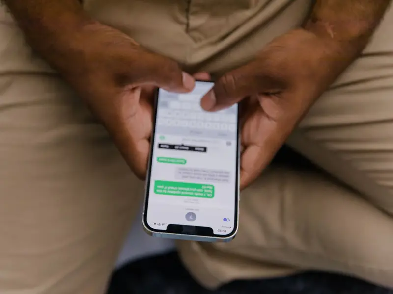 Two hands holding a smartphone that shows a back-and-forth text conversation