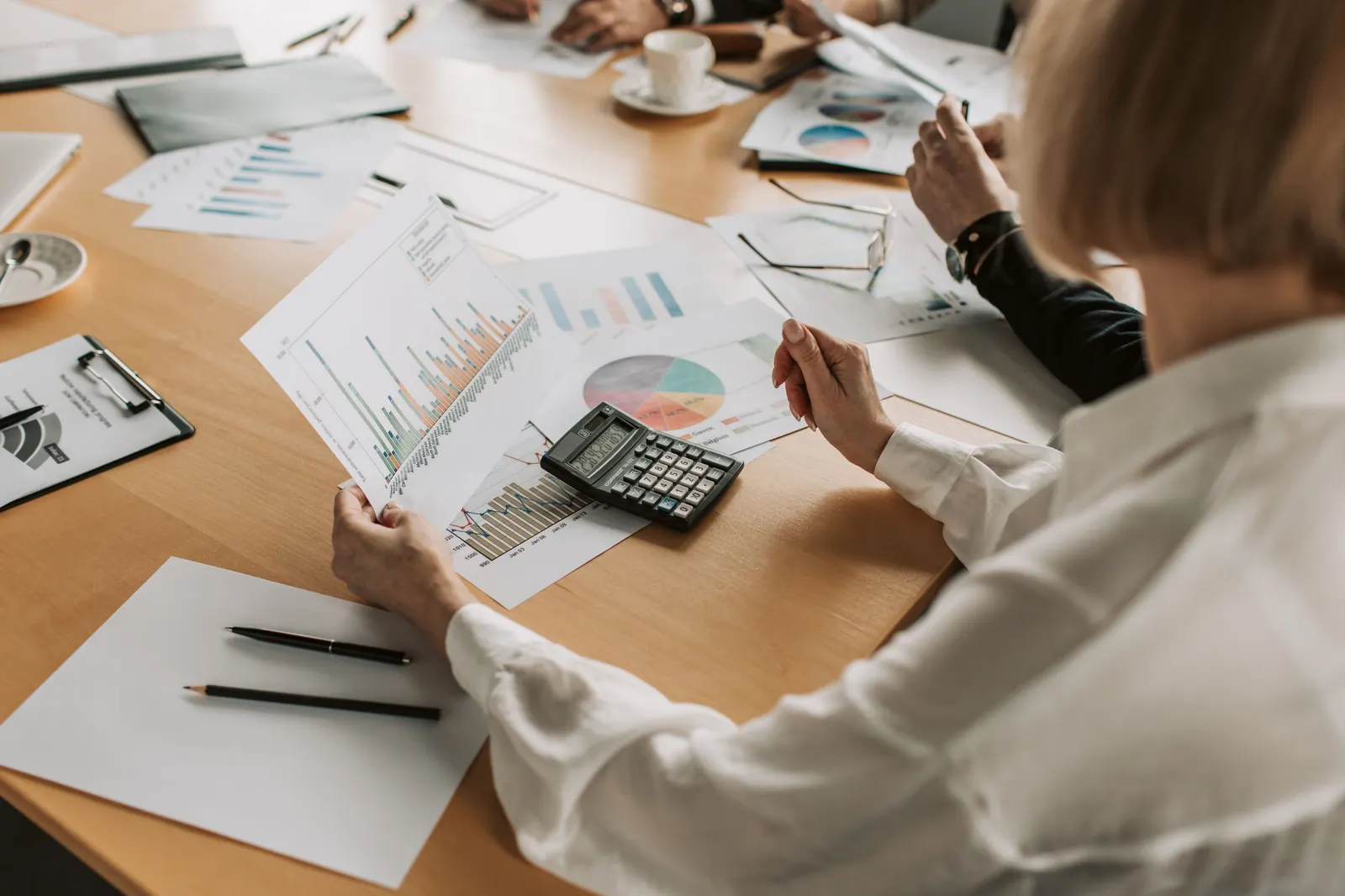 Two people at a table going through printed charts and figures together.