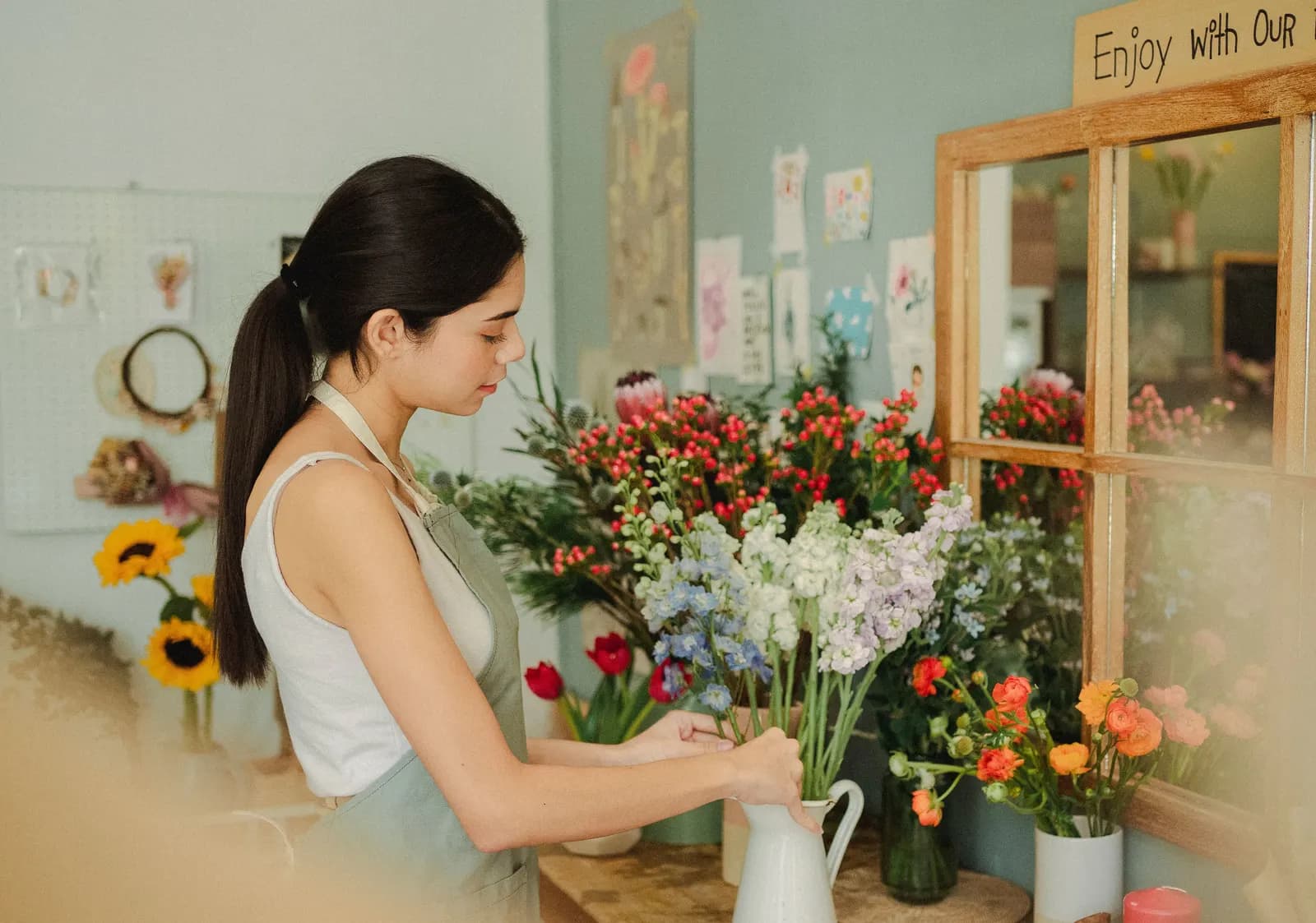 A florist arranging fresh flowers into a vase in a flower studio.