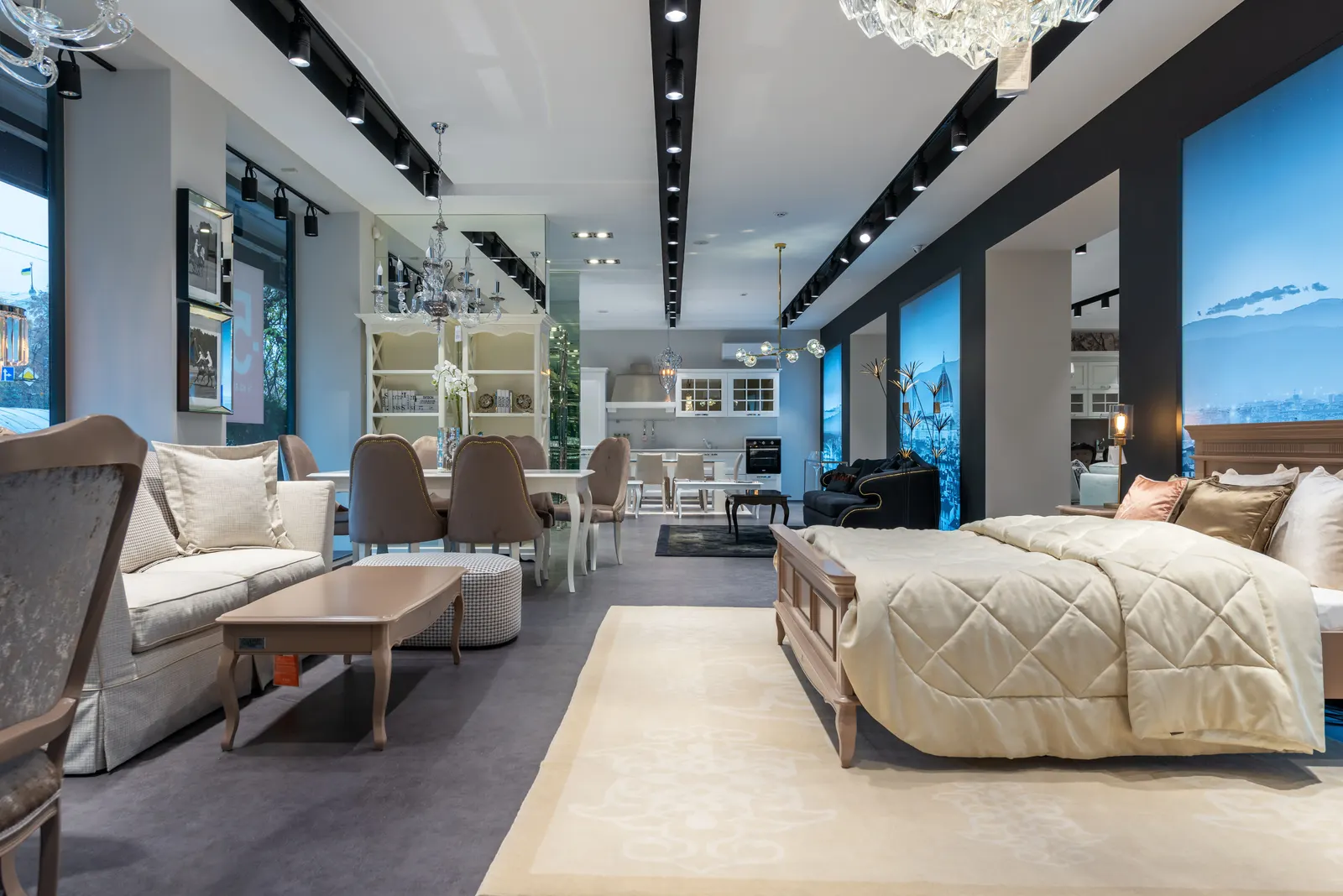 A furniture showroom with a made-up bed in front of a sofa and a dining table.
