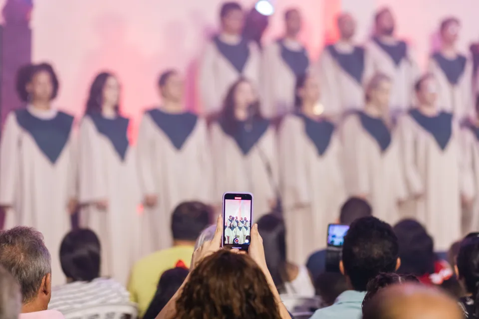 An audience filming a choir's performance on their phones.