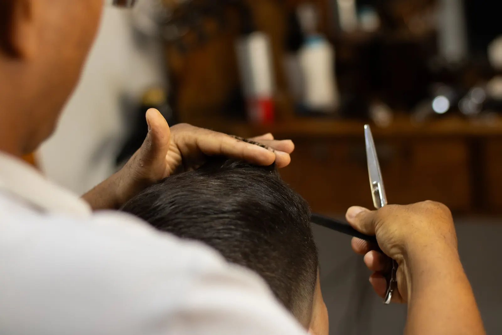 A barber cutting a man's hair with scissors and a comb.