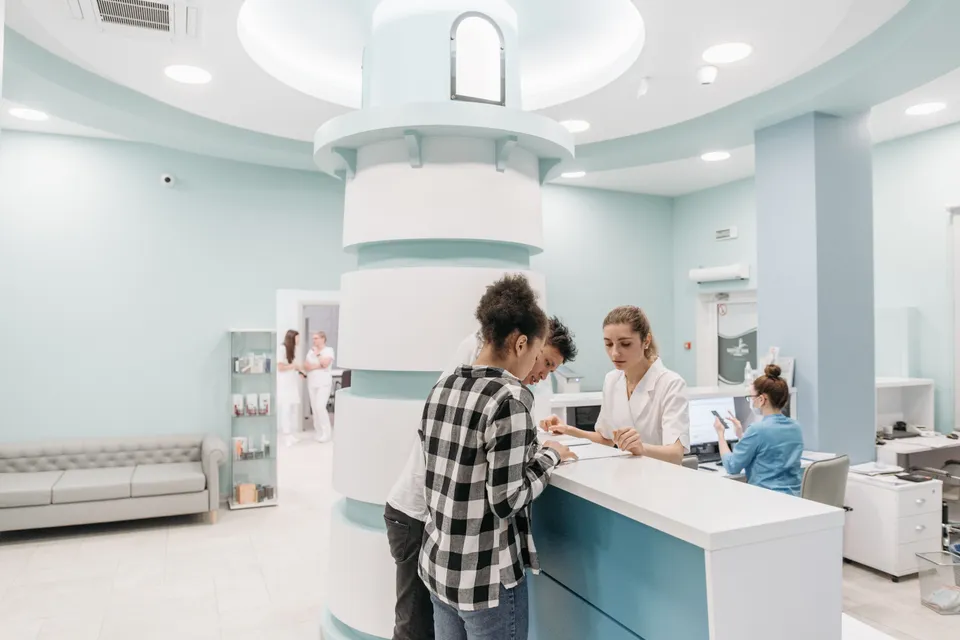 Patients checking in at the reception desk of a bright, modern clinic.