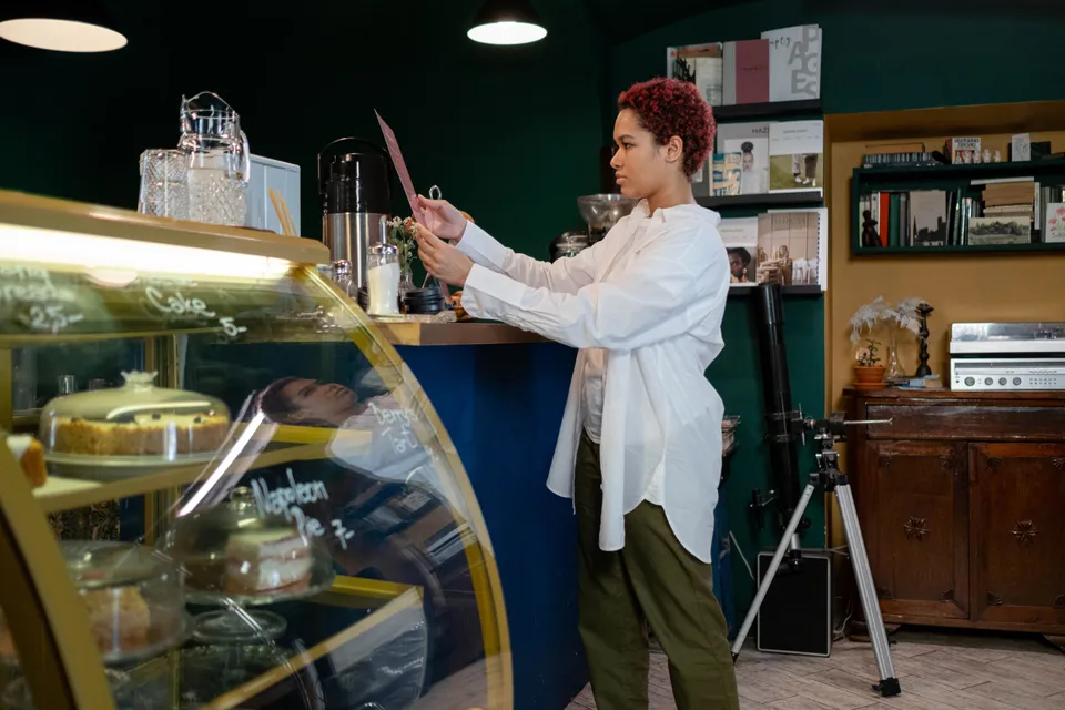 A woman at a café counter holding up a menu card.