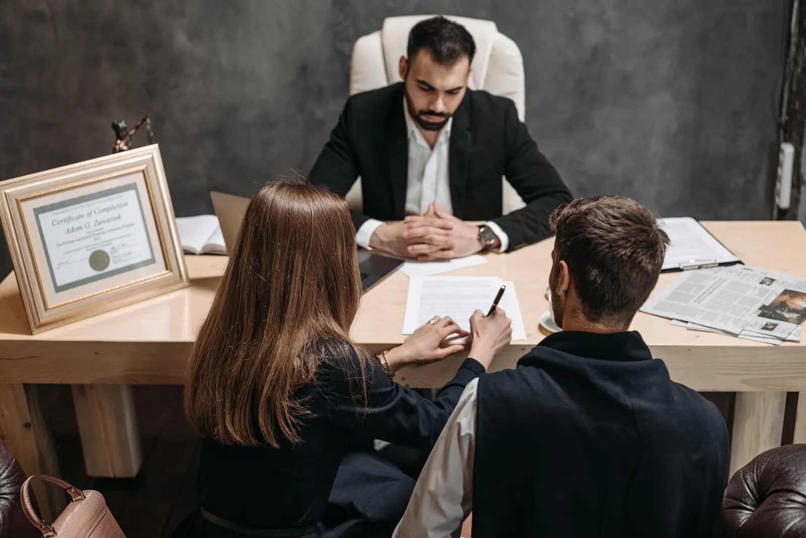 A lawyer going through documents across his desk with two people sitting opposite.