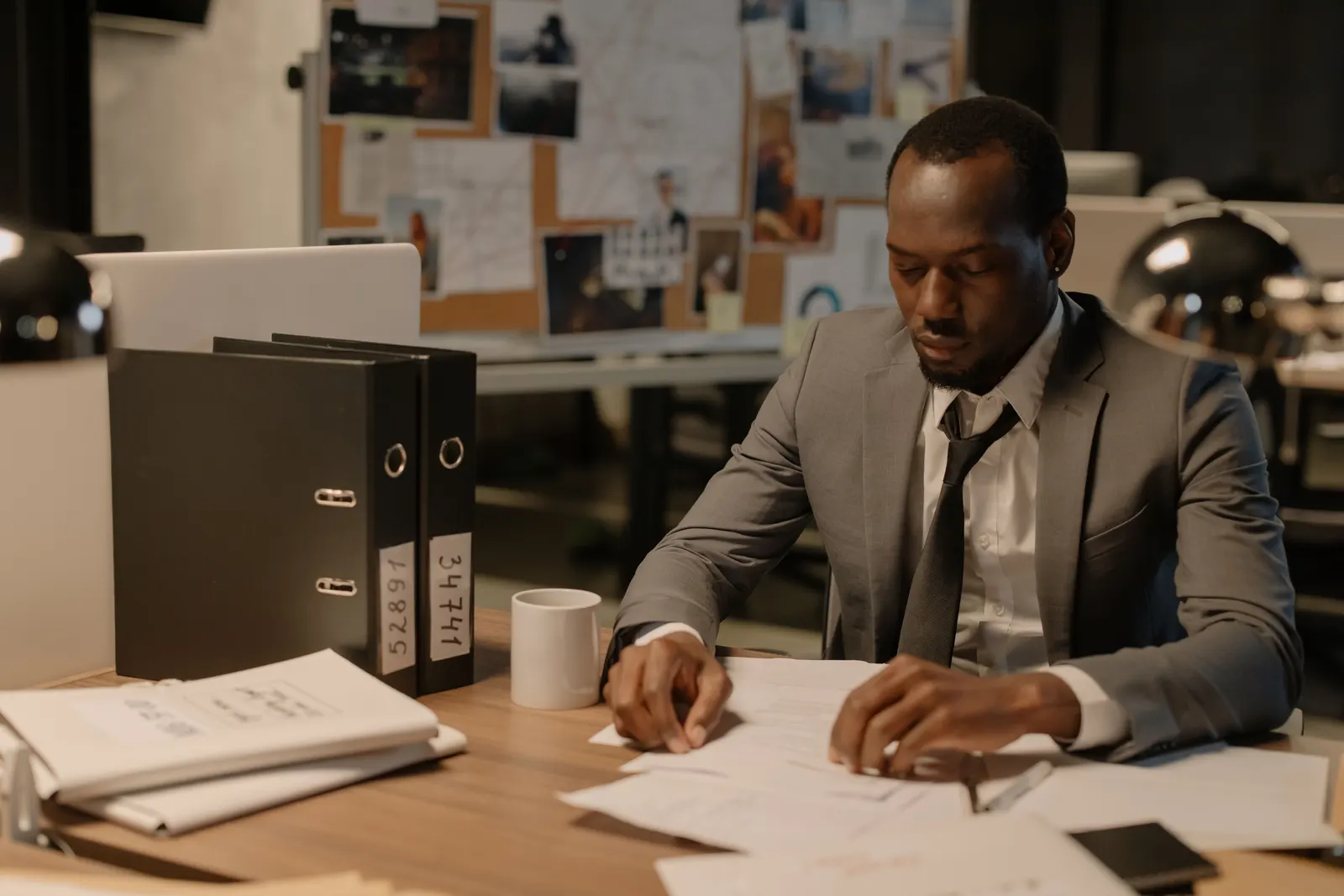 A lawyer working late at a desk with ring binders of case files beside him.