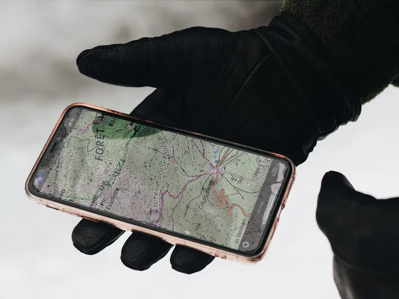 A gloved hand holding a phone that shows a map of the surrounding area