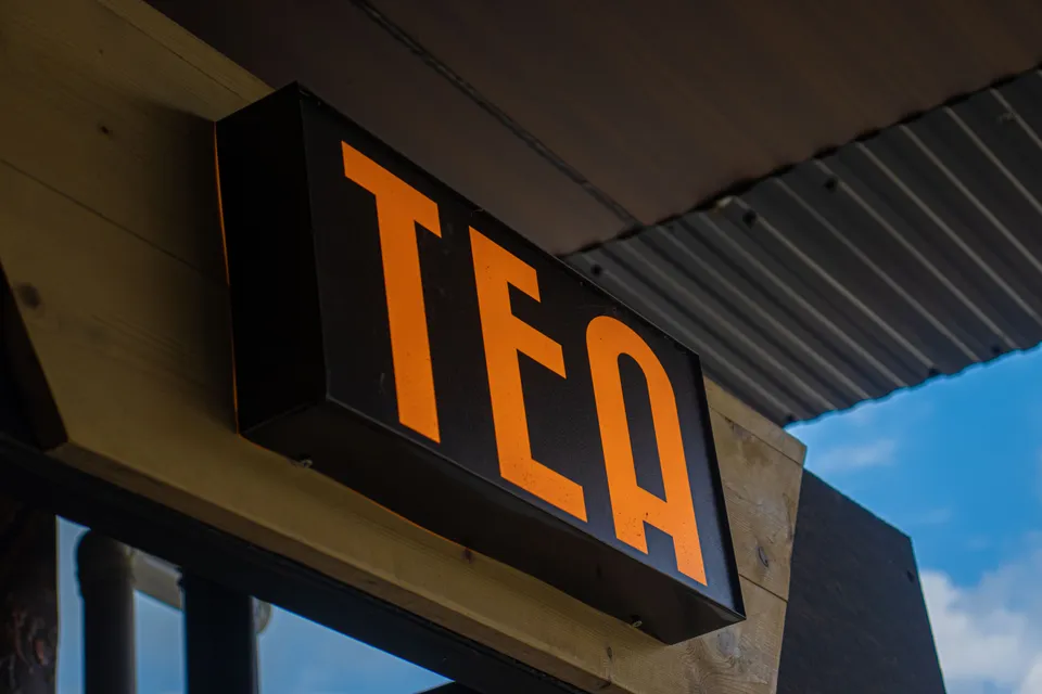 A shop sign reading TEA in bold orange letters above a doorway.