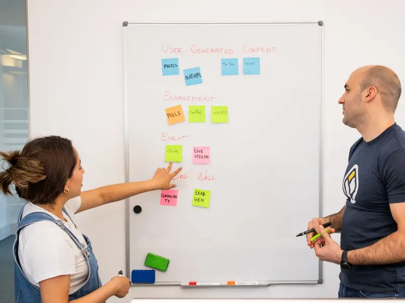 Two people planning at a whiteboard covered in coloured sticky notes
