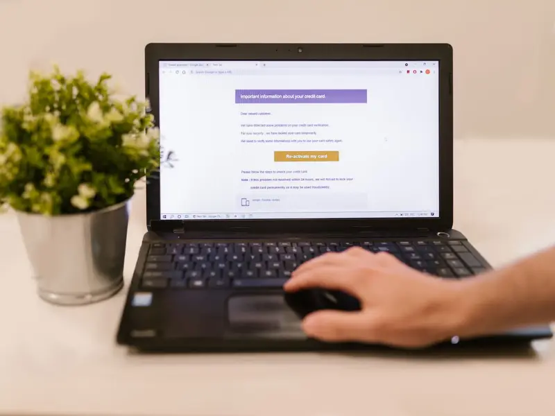 A hand on a laptop's touchpad with a marketing email open on the screen