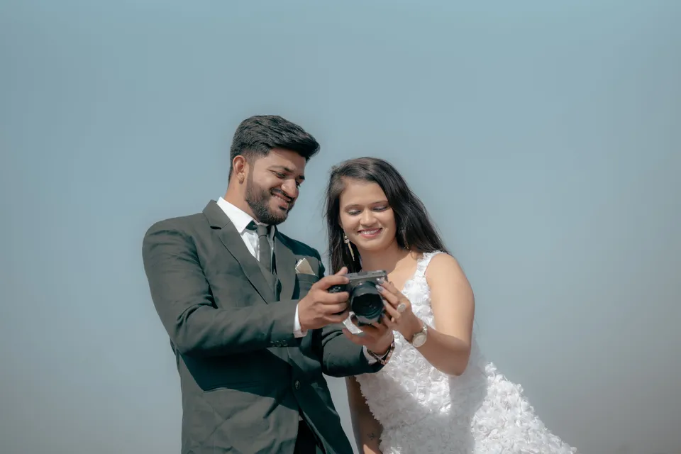 A bride and groom looking at photos on the back of a camera during a shoot.
