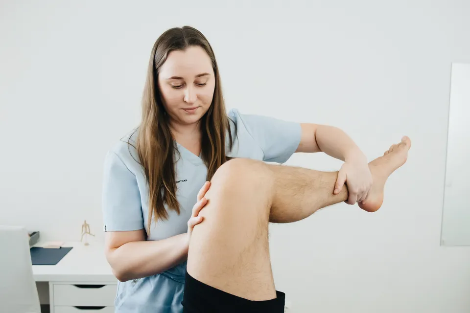 A physiotherapist bending a patient's leg at the knee during a treatment session.
