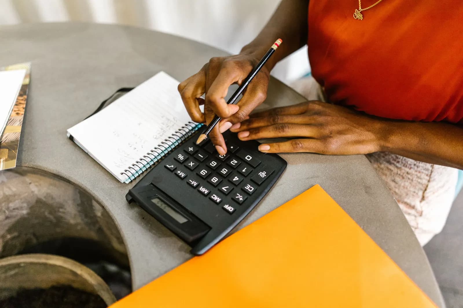 Hands working through figures with a calculator, a pencil and a notebook.