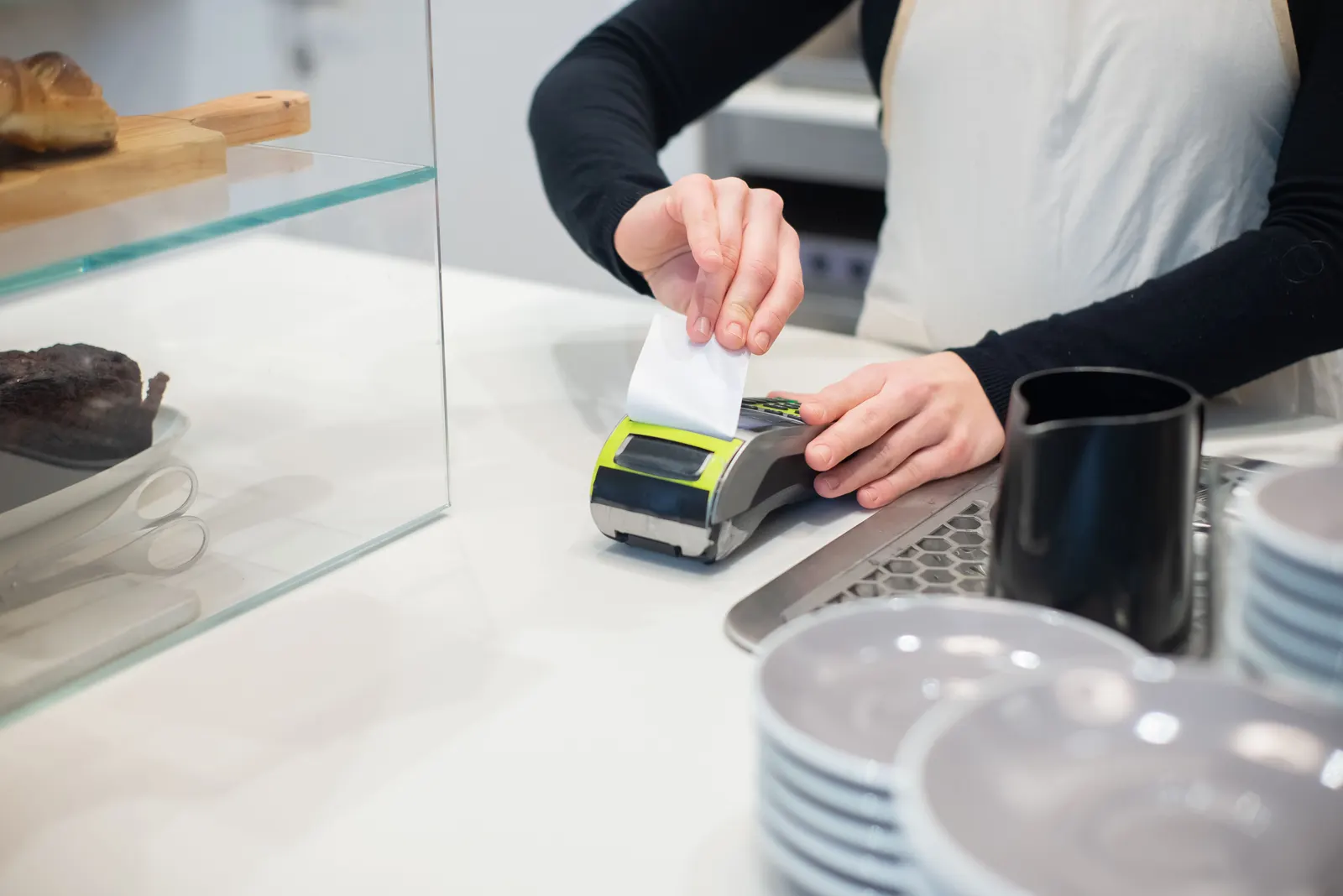 A receipt printing from a card terminal on a cafe counter as it is handed over.