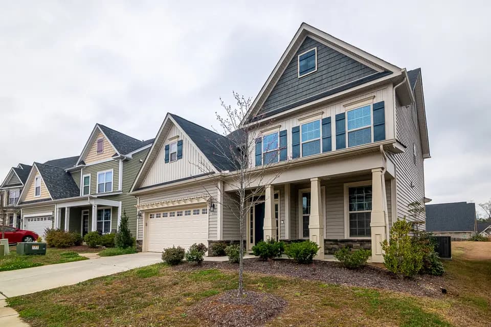 A row of newly built houses with driveways and young lawns.
