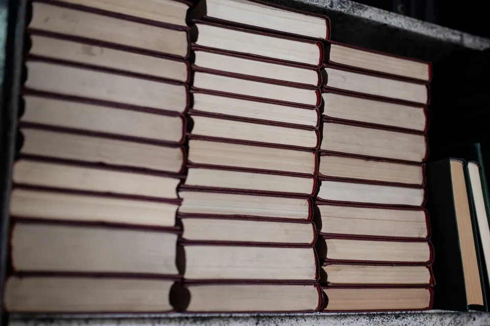 Rows of plain hardback books stacked neatly on a shelf.