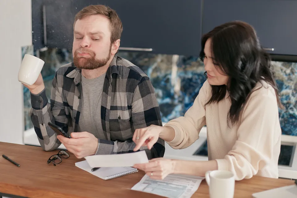 A couple going through bills together at their kitchen counter.