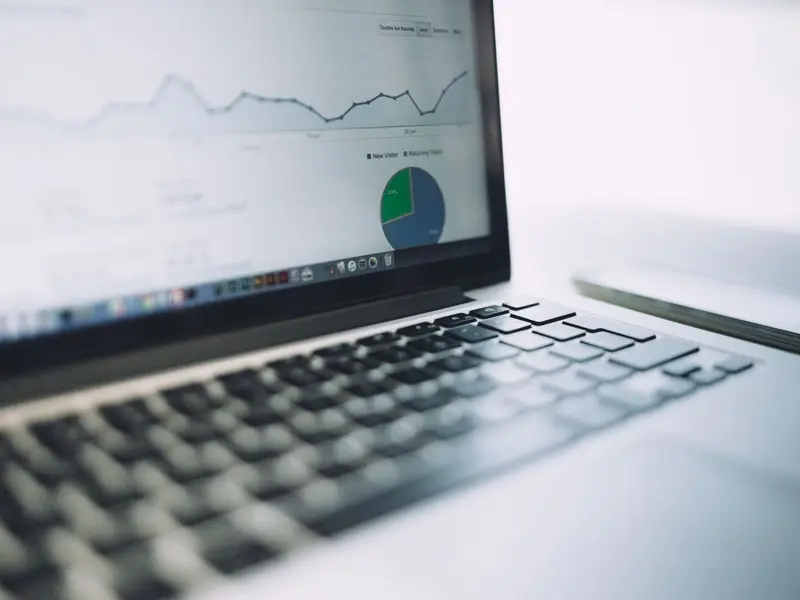 A laptop showing a campaign performance chart with a line graph and a pie chart