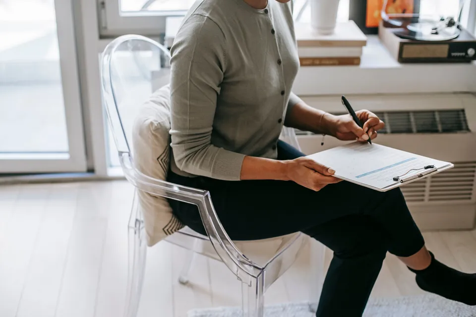 A therapist sitting with a clipboard, writing notes during a session.