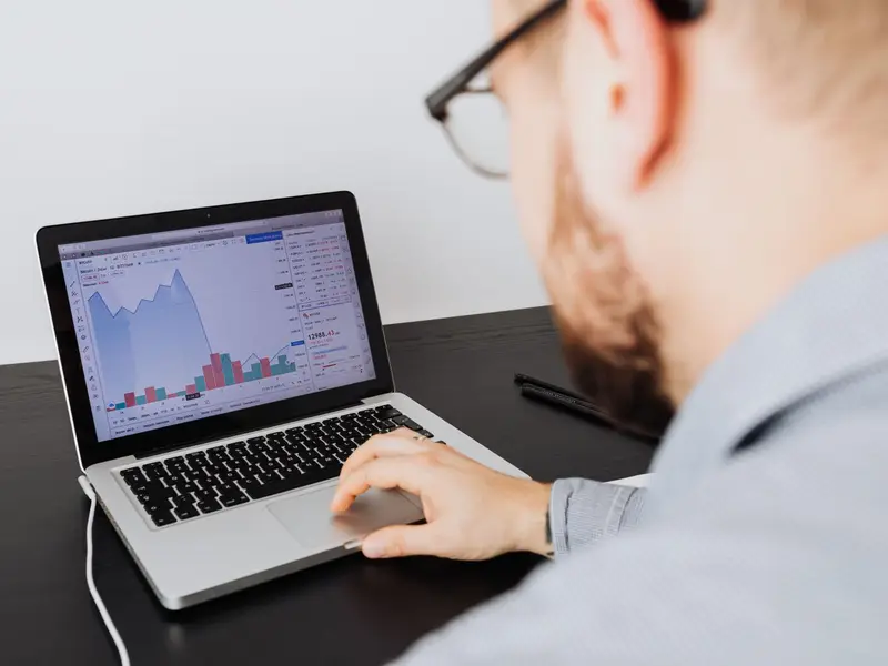 A man at a laptop studying website traffic charts on the screen