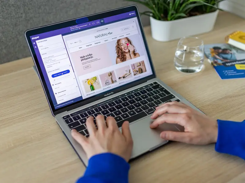 Hands typing on a laptop that shows an online shop's homepage being edited